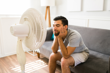 man cooling off through electric fan